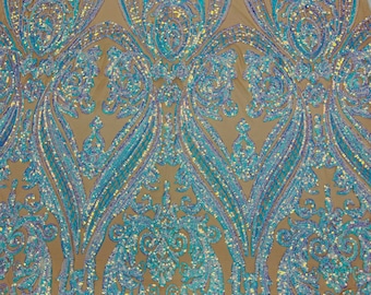Op de afbeelding: Close-up van een stof met een beige mesh achtergrond, versierd met ingewikkelde, symmetrische patronen in tinten turquoise en iriserende pailletten. Het ontwerp bevat bloem- en paisley-achtige motieven, waardoor een glanzend, getextureerd oppervlak ontstaat.