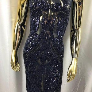 Puede incluir: Tela azul marino con lentejuelas y un patrón floral. Las lentejuelas son pequeñas y están densamente empaquetadas, creando un efecto brillante.