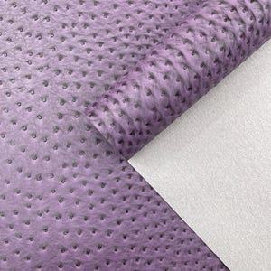 May include: A roll of lavender-colored faux leather with a textured, dotted pattern. The material is partially unrolled, revealing a white, smooth backing. The surface has a subtle, shaded effect.