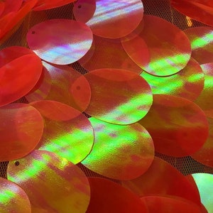 Könnte beinhalten: Nahaufnahme von schimmernden roten Pailletten auf einem Netzstoff. Die Pailletten sind oval geformt und haben eine holografische Oberfläche.