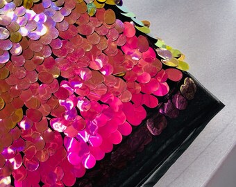 May include: A black fabric with iridescent sequins in a gradient pattern of yellow, pink, and purple.