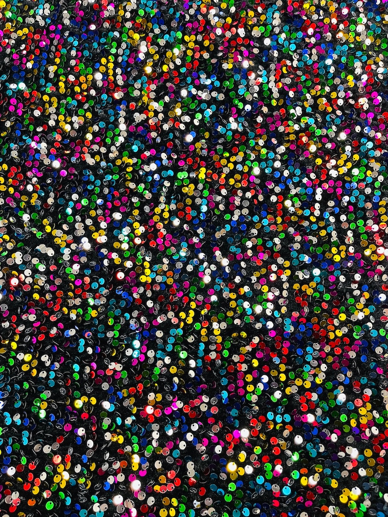 May include: A close-up of a fabric covered in iridescent sequins. The sequins are in a variety of colors, including silver, gold, red, blue, green, and purple.
