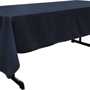 May include: A dark blue rectangular tablecloth draped over a table. The tablecloth has a smooth, wrinkle-free surface.