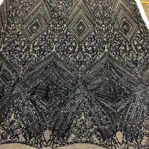 May include: Black sequined fabric with a geometric pattern. The sequins are arranged in a diamond shape and are interspersed with smaller sequins. The fabric is sheer and has a mesh backing.