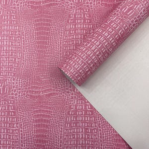 Peut inclure: Matériau en similicuir rose avec une texture peau de crocodile. Un rouleau et une pièce plate présentent le motif et la couleur. Le matériau a un envers blanc. Idéal pour l'artisanat.