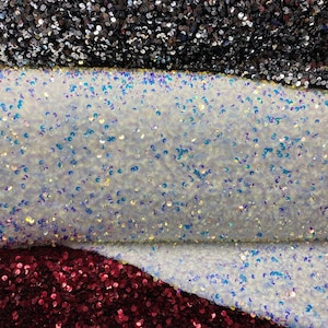 May include: Three swatches of sequined fabric. The top swatch is black, the middle swatch is iridescent white, and the bottom swatch is burgundy.