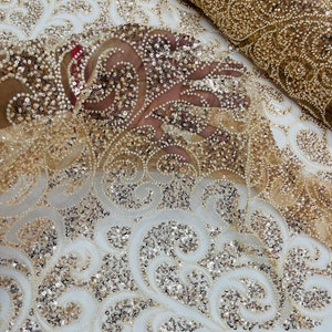 May include: Gold beaded and sequined fabric with a swirl pattern. The fabric is sheer and has a delicate texture.