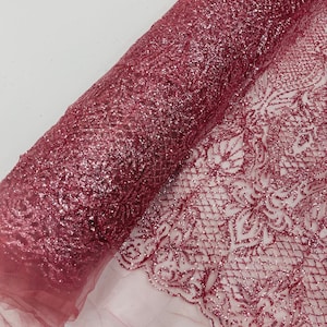 May include: Pink glitter tulle fabric with a delicate floral pattern. The fabric is soft and sparkly, making it perfect for adding a touch of glamour to any project.