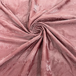 Könnte beinhalten: Nahaufnahme eines rosa Stoffes mit Schlangenhautmuster. Der Stoff ist drapiert und gefaltet und zeigt seine Textur und seinen Glanz.