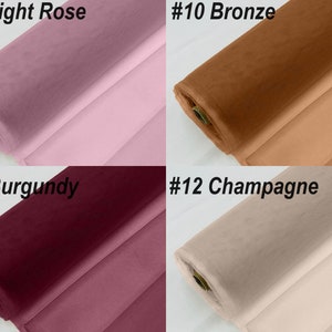 May include: Four rolls of tulle fabric in different colours: bright rose, bronze, burgundy, and champagne.
