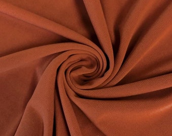 May include: Close-up of a rust-colored fabric with a ribbed texture. The fabric is folded and draped, showing its soft and drapey quality.