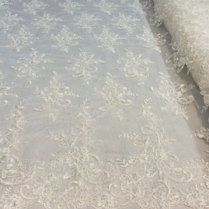 May include: White floral lace fabric with a delicate pattern. The lace is on a mesh background and has a scalloped edge.