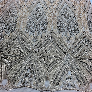 May include: Gold and black sequined fabric with a geometric pattern. The fabric has a sheer mesh backing.