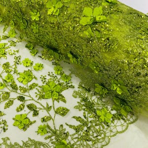 May include: Green floral lace fabric with 3D flowers and glitter. The fabric has a delicate mesh base and is perfect for adding a touch of elegance to any project.