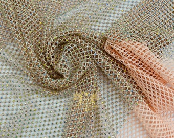 May include: A close-up of a peach and gold mesh fabric with iridescent rhinestones. The fabric is a sheer, lightweight material with a diamond-shaped pattern.