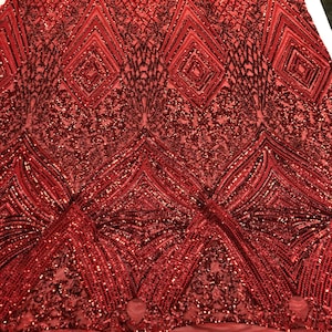 May include: Red sequined fabric with a geometric pattern. The sequins are arranged in a diamond shape and are sewn onto a mesh backing.