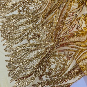 May include: Gold sequined fabric with a delicate floral pattern. The fabric is sheer and has a soft, flowing texture.