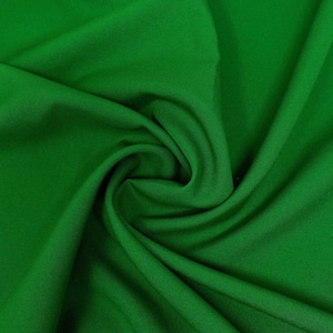 Op de afbeelding: Een close-up van een gladde, groene stof met zachte plooien en kreukels. De stof is effen van kleur zonder patronen of ontwerpen.