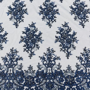 May include: Navy blue beaded lace fabric with a floral pattern. The lace has a scalloped edge.
