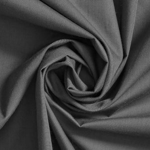 May include: A close-up of a dark gray fabric with a soft, smooth texture. The fabric is folded and draped in a way that creates a swirling pattern.