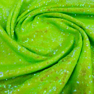 May include: A close-up of lime green fabric with iridescent sequins. The fabric is gathered and folded, showing the texture of the sequins.