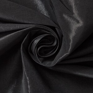 May include: Close-up of a rolled-up, black fabric with a subtle sheen. The fabric's folds create a swirling pattern, highlighting its texture and depth. The material appears smooth and luxurious, suitable for apparel or decorative projects.