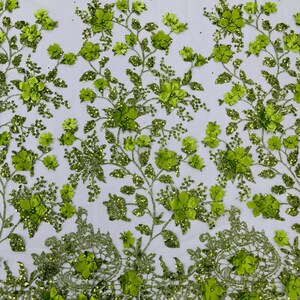 May include: Green floral lace fabric with 3D flowers and glitter. The fabric has a delicate, intricate design and is perfect for adding a touch of elegance to any project.