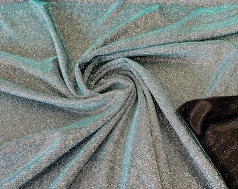 Könnte beinhalten: Nahaufnahme eines teal- und silberfarbenen, glitzernden Stoffes. Der Stoff ist gefaltet und hat eine weiche, schimmernde Textur.