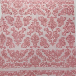 Op de afbeelding: Roze parelversierd kantstof met een bloemenpatroon. De kant is delicaat en heeft een zachte, vrouwelijke uitstraling.