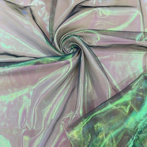 May include: Iridescent sheer fabric with a green and purple shimmer. The fabric is folded and draped, showing its texture and sheen.
