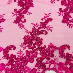 May include: Pink mesh fabric with a magenta floral lace design. The lace features intricate swirls and sequins.