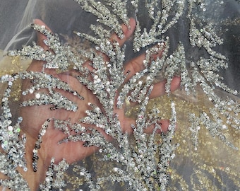 May include: Silver and gold sequined fabric with a delicate mesh backing. The sequins are arranged in a floral pattern.