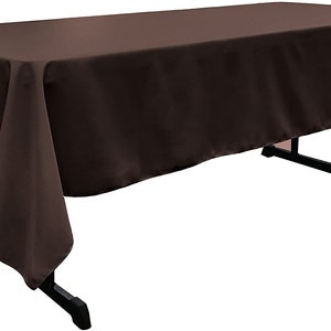 May include: A brown rectangular tablecloth with a smooth, wrinkle-free surface. The tablecloth is draped over a table and hangs down on all sides.