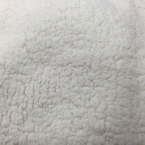 May include: Close-up of a white, fluffy fabric with a textured surface. The fabric has a soft, plush feel.