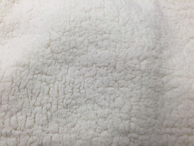 May include: Close-up of a white, fluffy fabric with a textured surface. The fabric has a soft, plush feel.