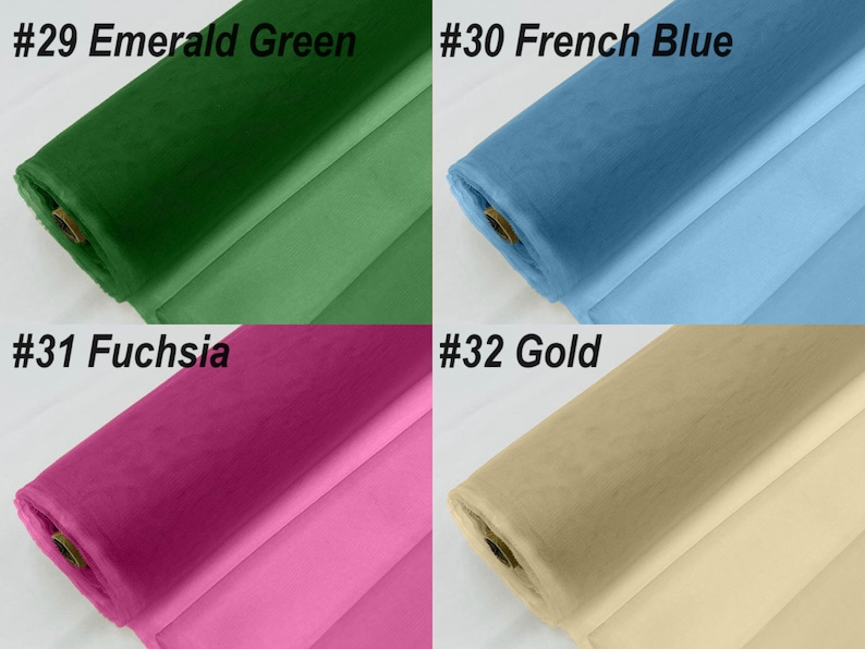 May include: Four rolls of tulle fabric in different colours: emerald green, French blue, fuchsia, and gold. The fabric is rolled up and the ends are visible.