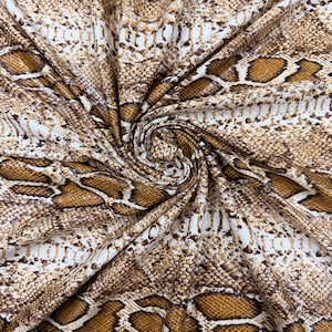 Könnte beinhalten: Nahaufnahme eines Stoffes mit Schlangenmuster. Der Stoff weist ein sich wiederholendes Design aus braunen, beigen und weißen Schuppen auf, wodurch eine realistische Reptilienhautstruktur entsteht. Das Material ist drapiert und zeigt Falten und Schatten.