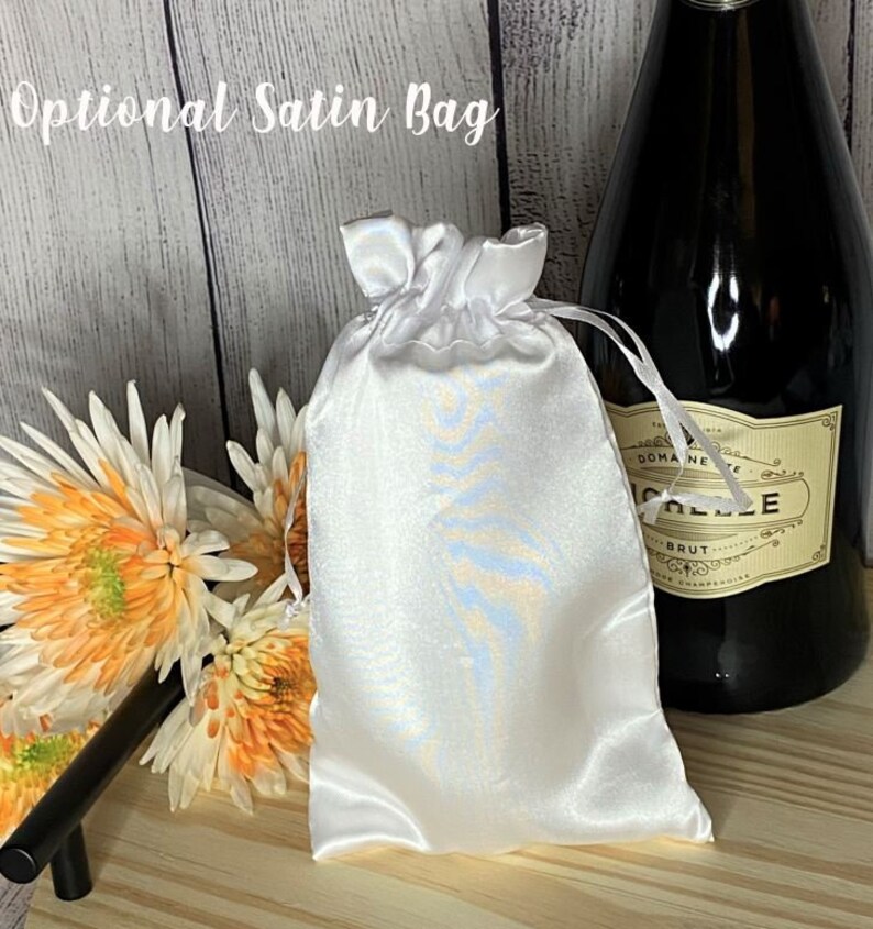 May include: A white satin bag with a blue and white pattern. The bag is tied with a white ribbon and is sitting on a wooden surface.