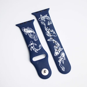 以下が含まれることがあります： 白いコイの魚のデザインが施された青いシリコン製の腕時計バンド2本。バンドはApple Watch用に設計されています。