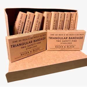 May include: A cardboard box filled with several beige boxes of triangular bandages. Each box is labeled with the dimensions 40 inches by 40 inches by 56 inches, and the text "TRIANGULAR BANDAGE". The boxes are labeled "STERILIZED" and include two safety pins.