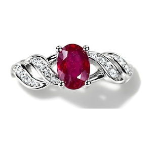 May include: A silver-toned ring featuring a large, oval-cut deep red ruby at the center, held by four prongs. The band has a twisted, bypass-style design on both sides, accented with small, clear, round-cut white stones set along the metal curves.