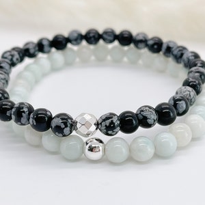 Peut inclure: Deux bracelets, l'un noir avec des perles d'obsidienne à flocons de neige blancs et l'autre blanc avec des perles de jade blanc, avec des perles d'espacement argentées.