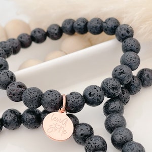 May include: Two black lava stone beaded bracelets with a rose gold charm that says "Love Story".
