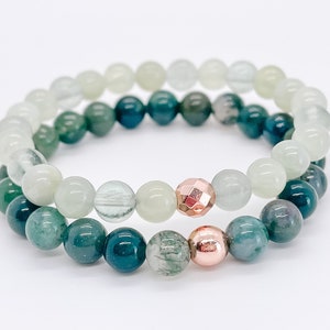 May include: Two bracelets made of green and white agate beads with rose gold accents.