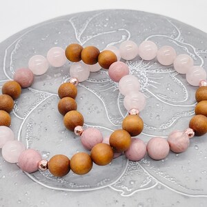 Peut inclure: Deux bracelets, l'un avec des perles roses et brunes, l'autre avec des perles rose clair et brunes. Les bracelets sont sur un fond gris avec un motif floral.