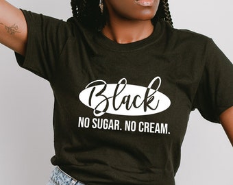 May include: Black t-shirt with the text "Black No Sugar No Cream" in a white oval. The model is wearing a black hat and light blue ripped jeans. The model is also wearing bracelets.
