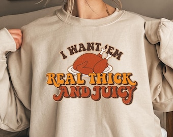 May include: A beige sweatshirt with a graphic print of a turkey and the text "I want 'em real thick and juicy".