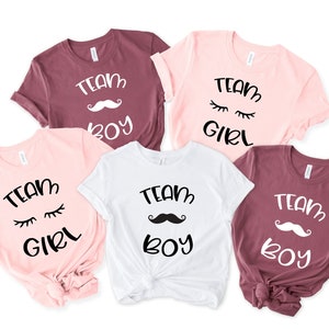 May include: Five t-shirts in different colours with the text "Team Boy" and "Team Girl" printed on them. The shirts feature a moustache and eyelashes graphic.