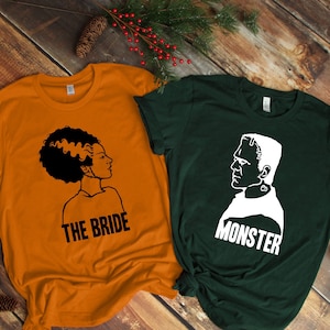 May include: Two t-shirts with a Halloween theme. The orange shirt has a black silhouette of a woman with the text "The Bride". The green shirt has a white silhouette of a man with the text "Monster".