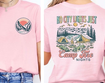 May include: Pink t-shirt with a graphic of a mountain scene and the text "NO CITY LIGHTS JUST CAMP FIRE NIGHTS" on the back.